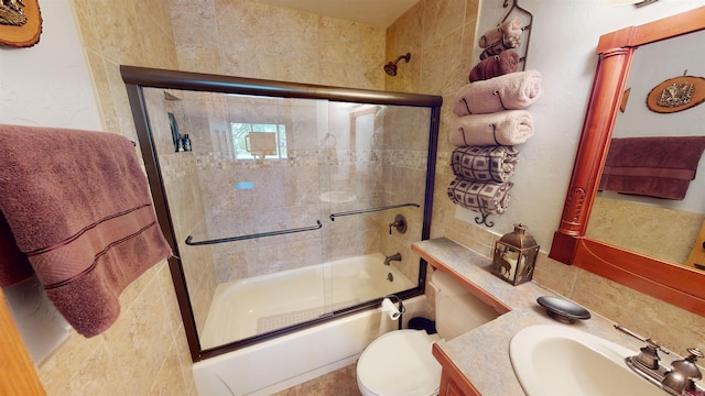 full bathroom featuring vanity, shower / bath combination with glass door, toilet, and decorative backsplash