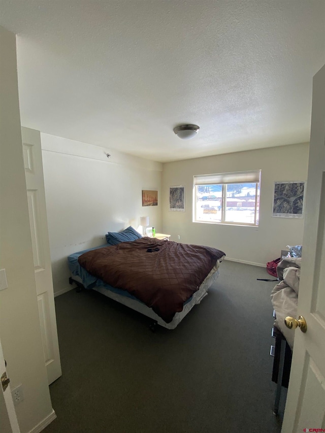 bedroom featuring a textured ceiling and dark carpet