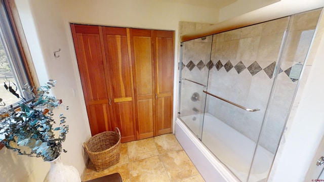 bathroom with shower / bath combination with glass door and tile flooring