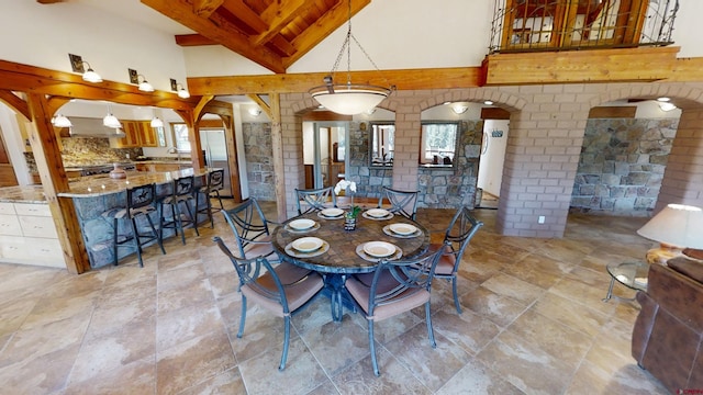 tiled dining area featuring a towering ceiling and beamed ceiling