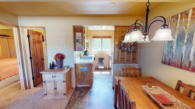 dining area featuring sink, an inviting chandelier, and dark carpet