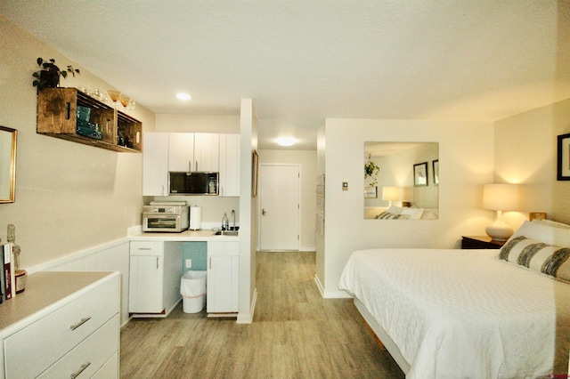 bedroom with light hardwood / wood-style flooring and sink