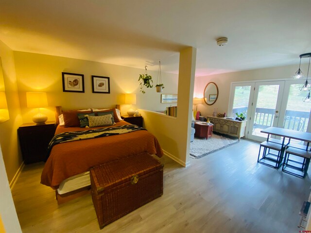 bedroom featuring access to exterior, light hardwood / wood-style floors, and french doors