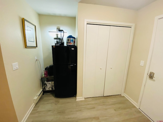 bedroom with light hardwood / wood-style floors, black refrigerator, and a baseboard radiator