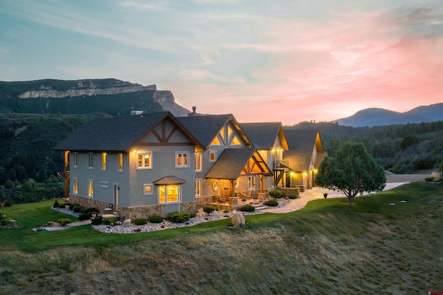 back house at dusk featuring a yard and a mountain view