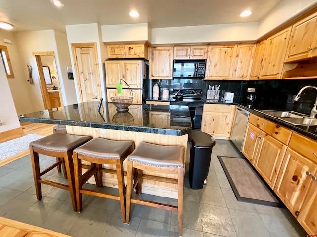 kitchen featuring backsplash, black appliances, sink, light tile floors, and a center island