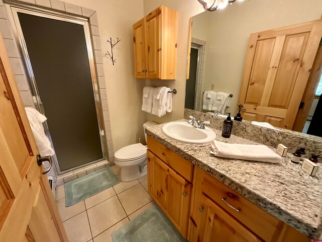 bathroom featuring an enclosed shower, vanity, tile floors, and toilet