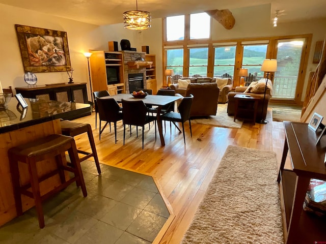 dining area featuring a notable chandelier, a fireplace, a water view, and light hardwood / wood-style floors