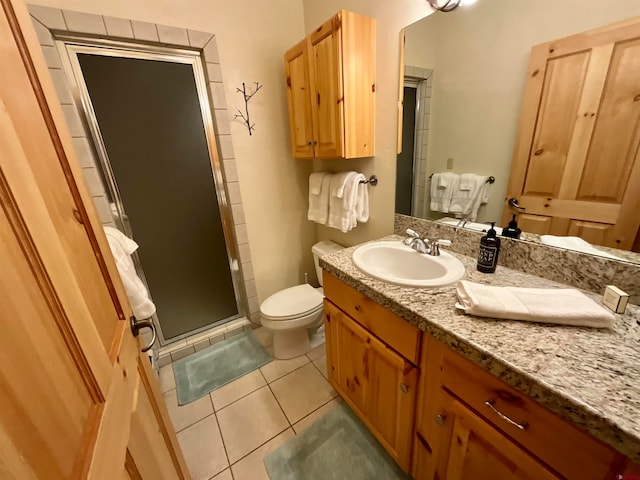 bathroom featuring a shower with shower door, tile floors, toilet, and vanity