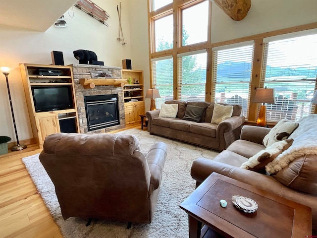 living room featuring a towering ceiling, a fireplace, and light hardwood / wood-style floors