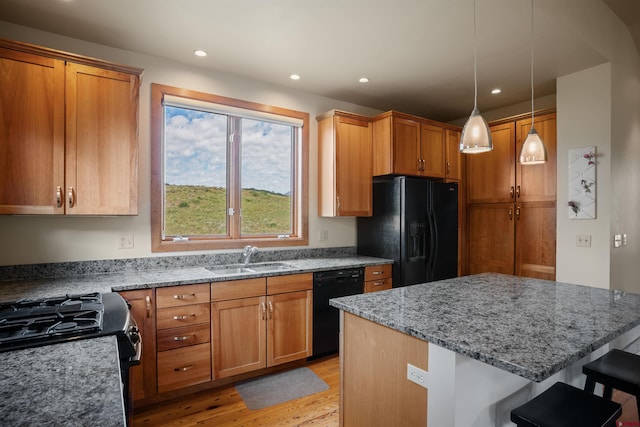 kitchen featuring black appliances, a breakfast bar, sink, light hardwood / wood-style flooring, and pendant lighting