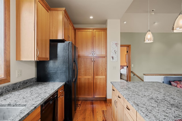 kitchen with decorative light fixtures, light stone counters, light hardwood / wood-style floors, and black dishwasher