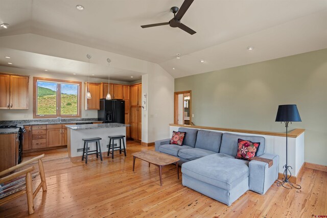 living room featuring ceiling fan, vaulted ceiling, and light hardwood / wood-style flooring