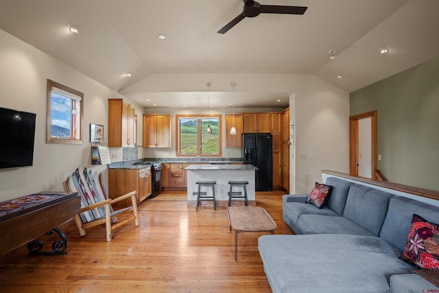 living room with vaulted ceiling, ceiling fan, and light wood-type flooring