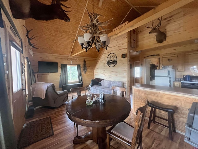 dining room with wood walls, dark hardwood / wood-style floors, and vaulted ceiling