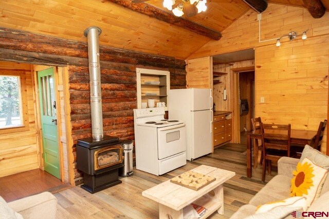 289 S Main St, Creede, CO 81130 - living area featuring lofted ceiling with beams, a wood stove, log walls, light wood finished floors, and wooden walls