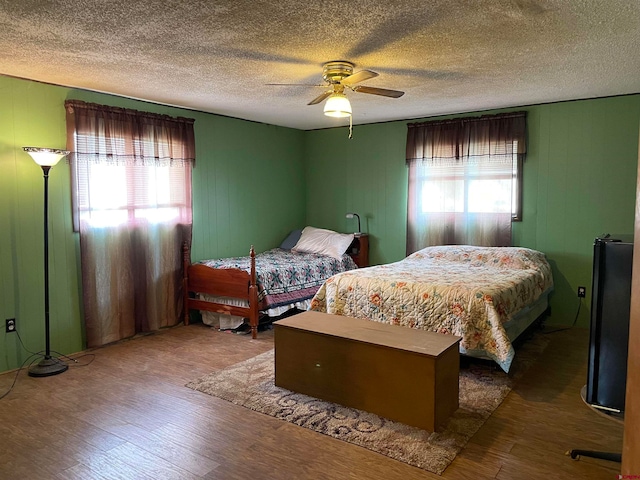 bedroom featuring dark wood-type flooring, ceiling fan, multiple windows, and a textured ceiling