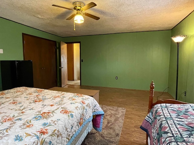 bedroom featuring light hardwood / wood-style floors, a textured ceiling, and ceiling fan