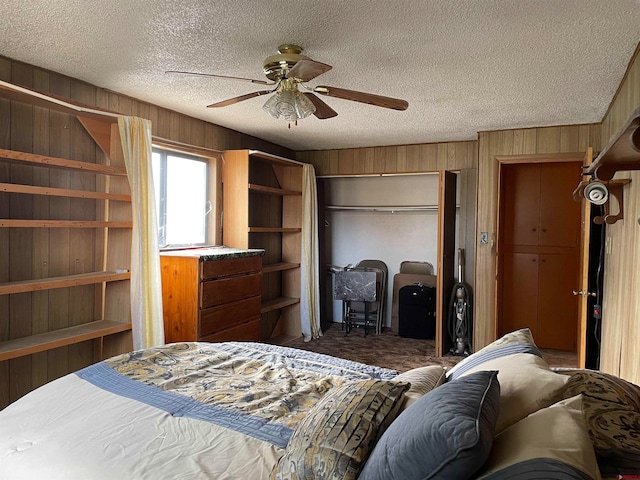 carpeted bedroom featuring a closet, wooden walls, a textured ceiling, and ceiling fan