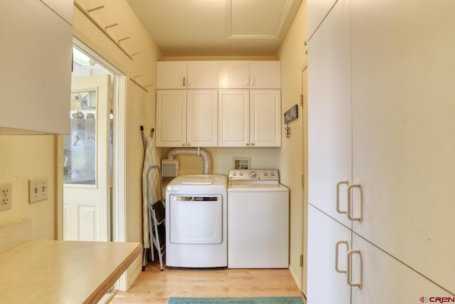 clothes washing area with washing machine and clothes dryer, cabinets, and light wood-type flooring