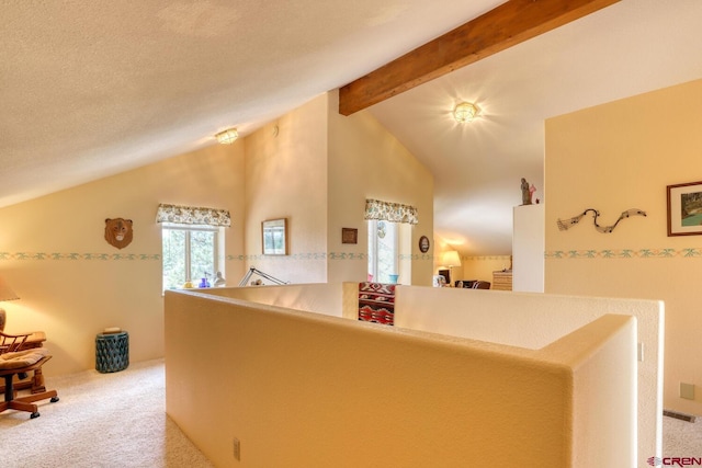 corridor with high vaulted ceiling, beam ceiling, a textured ceiling, and light colored carpet