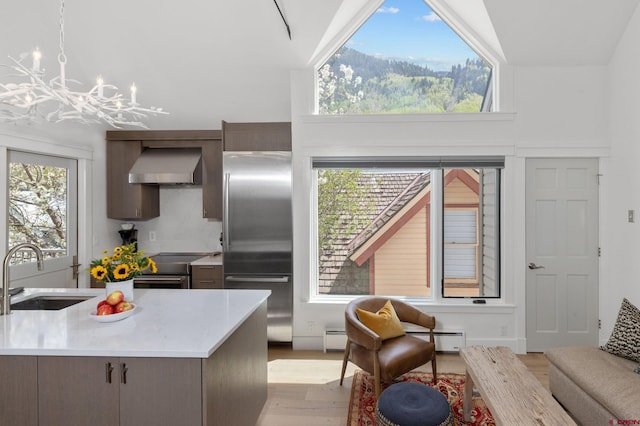 kitchen featuring a chandelier, wall chimney exhaust hood, lofted ceiling, light wood-type flooring, and sink