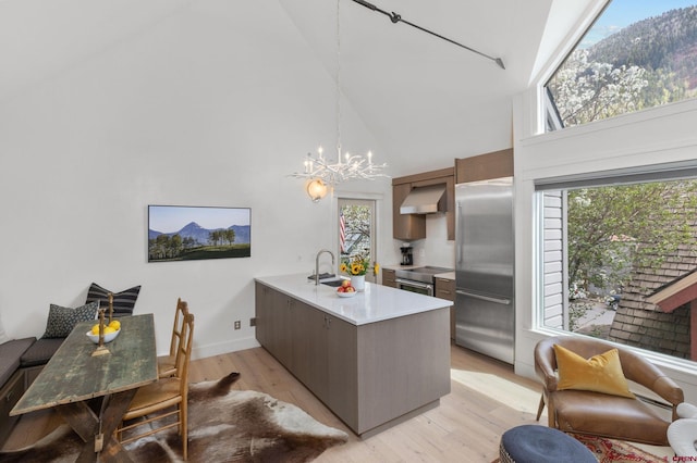 kitchen with light wood-type flooring, stainless steel built in refrigerator, plenty of natural light, and high vaulted ceiling