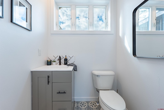 bathroom with tile floors, toilet, vanity, and a healthy amount of sunlight