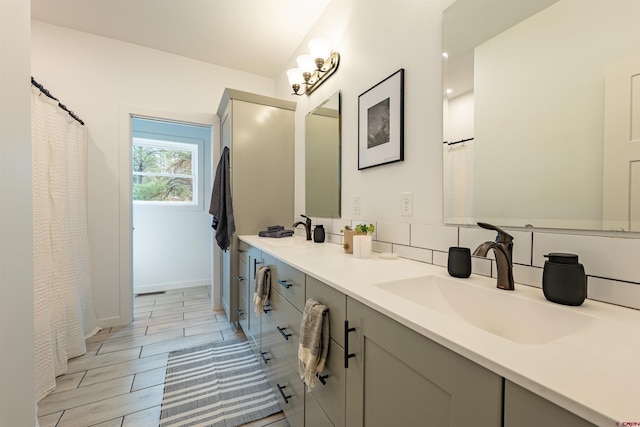 bathroom featuring oversized vanity, tile flooring, backsplash, and dual sinks