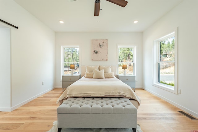 bedroom with ceiling fan, light hardwood / wood-style floors, and multiple windows