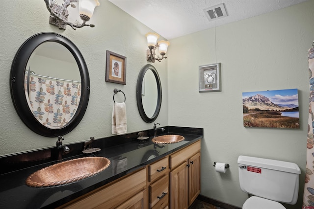 bathroom featuring dual sinks, toilet, oversized vanity, and a textured ceiling