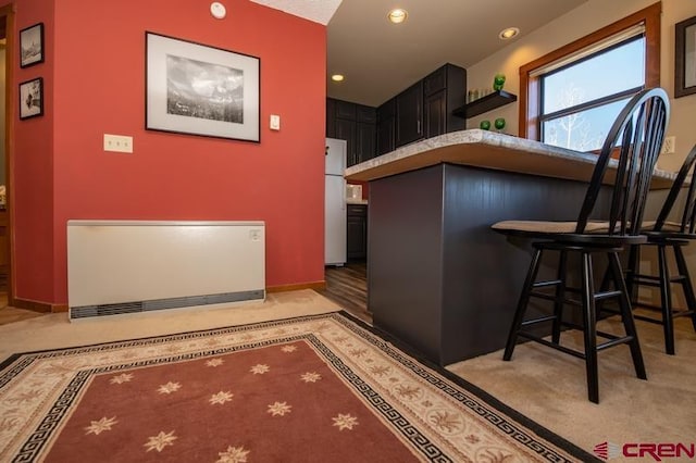 kitchen with light carpet, white refrigerator, and a breakfast bar area