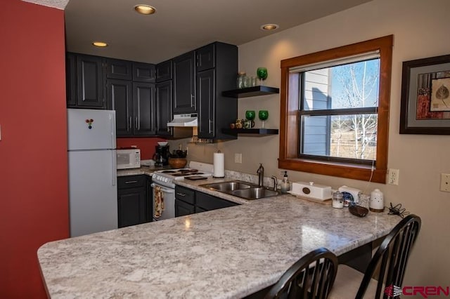 kitchen with white appliances, kitchen peninsula, a breakfast bar area, and sink