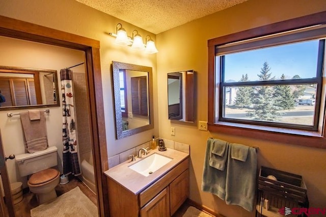 full bathroom featuring vanity with extensive cabinet space, shower / bathtub combination with curtain, toilet, and a textured ceiling