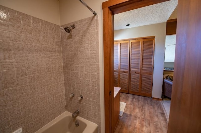 bathroom featuring vanity, tiled shower / bath combo, a textured ceiling, and hardwood / wood-style flooring