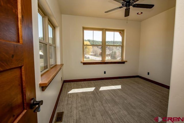 spare room featuring dark carpet and ceiling fan