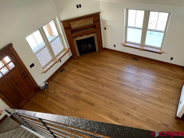 unfurnished living room with wood-type flooring and a towering ceiling