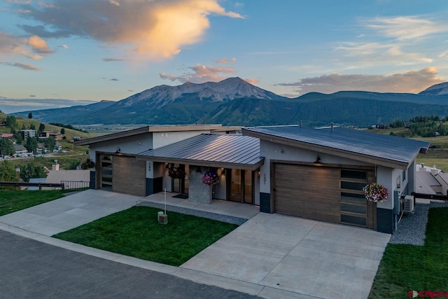 view of front of property featuring a garage, a mountain view, and a lawn