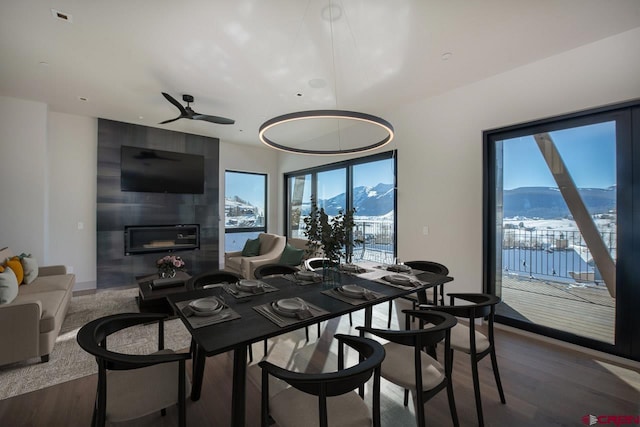 dining area featuring a large fireplace, hardwood / wood-style floors, and ceiling fan