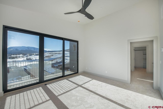 unfurnished room featuring a high ceiling, a mountain view, carpet floors, and ceiling fan