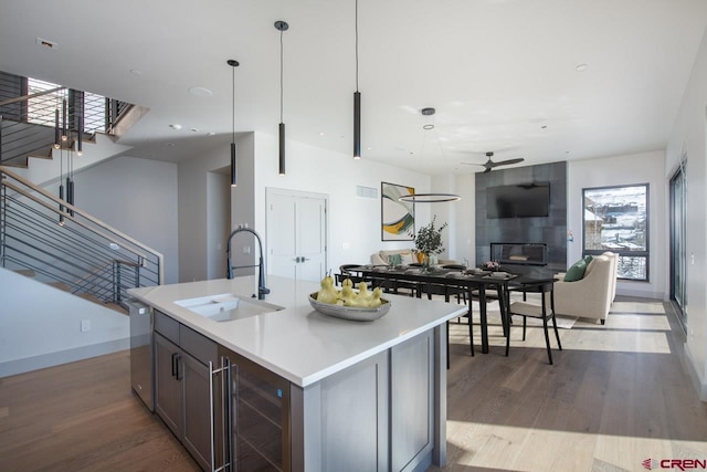 kitchen with a fireplace, dishwasher, sink, wine cooler, and hanging light fixtures