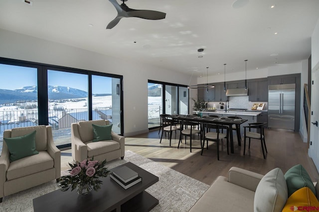 living room with a mountain view, hardwood / wood-style floors, and ceiling fan