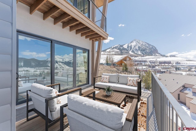 snow covered back of property with a mountain view and outdoor lounge area