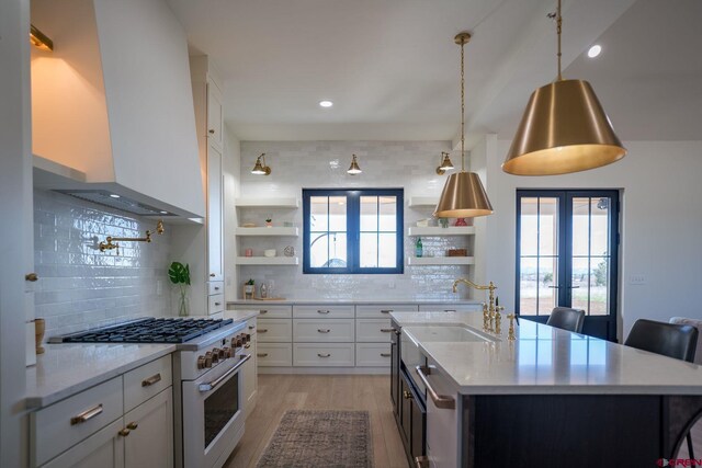 kitchen with a breakfast bar area, tasteful backsplash, white cabinets, wall chimney exhaust hood, and high end range