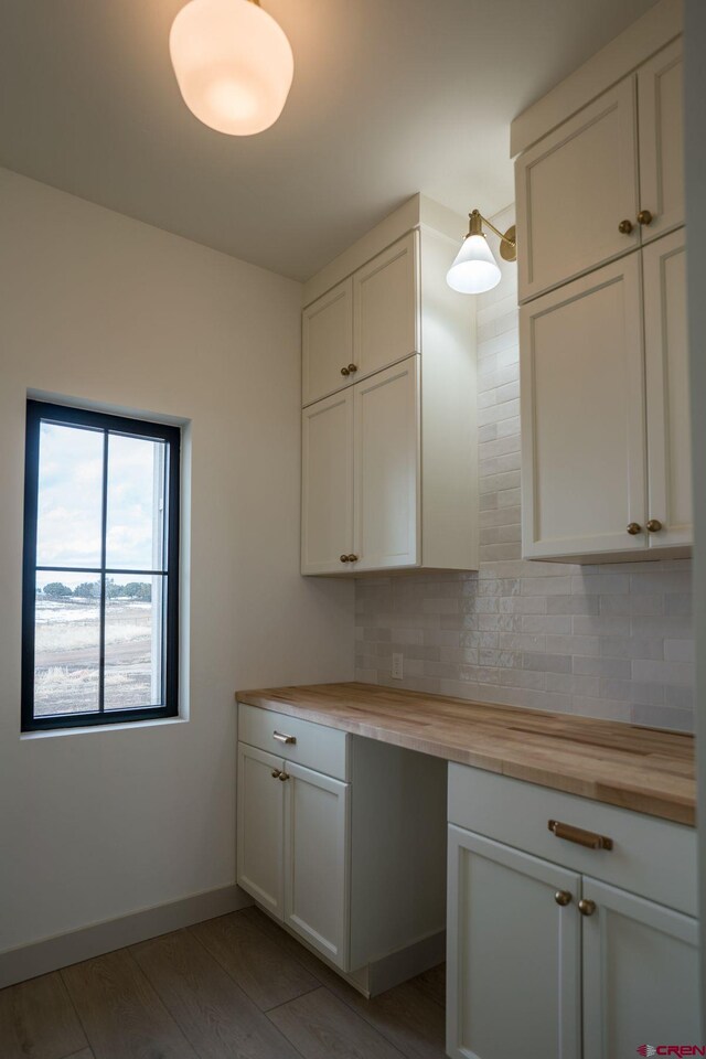 interior space with decorative backsplash, butcher block counters, white cabinetry, and light wood-type flooring