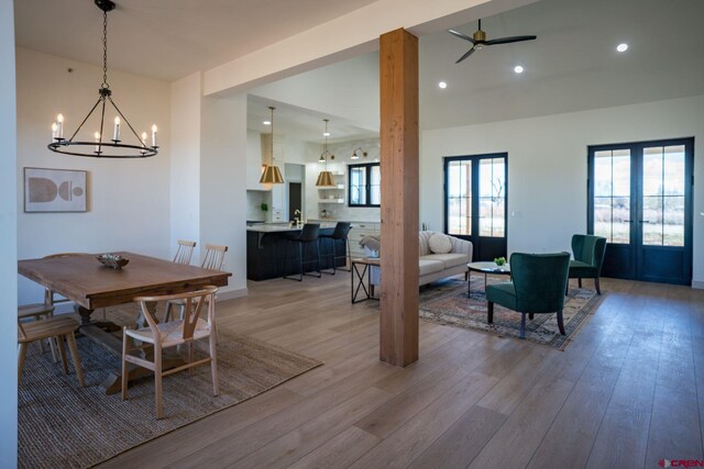 dining space featuring ceiling fan with notable chandelier, french doors, and light wood-type flooring