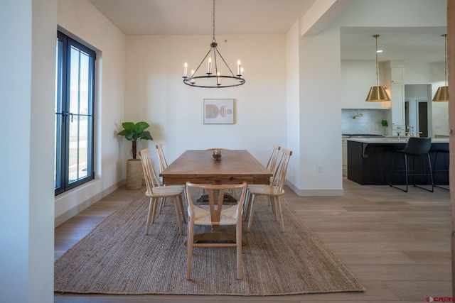 dining space with a healthy amount of sunlight, light hardwood / wood-style flooring, and a chandelier