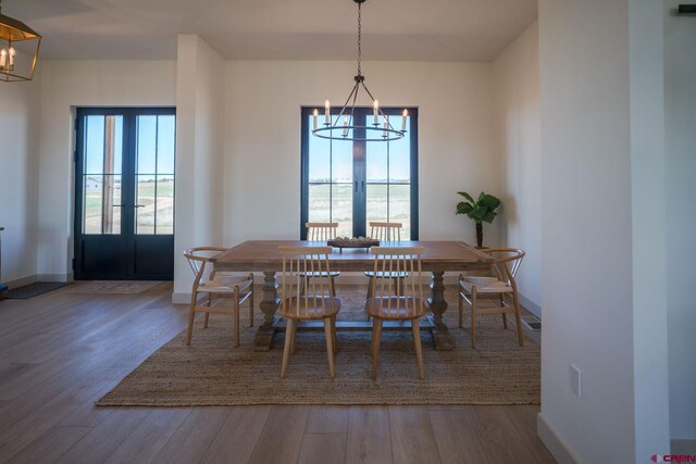 dining space with french doors, hardwood / wood-style flooring, a notable chandelier, and a wealth of natural light