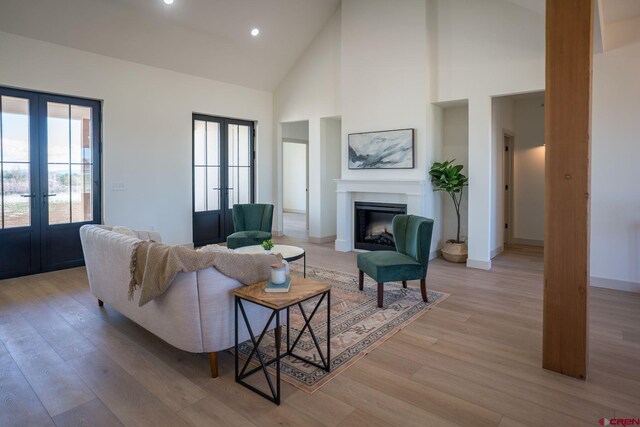 living room featuring french doors, a wealth of natural light, light wood-type flooring, and high vaulted ceiling