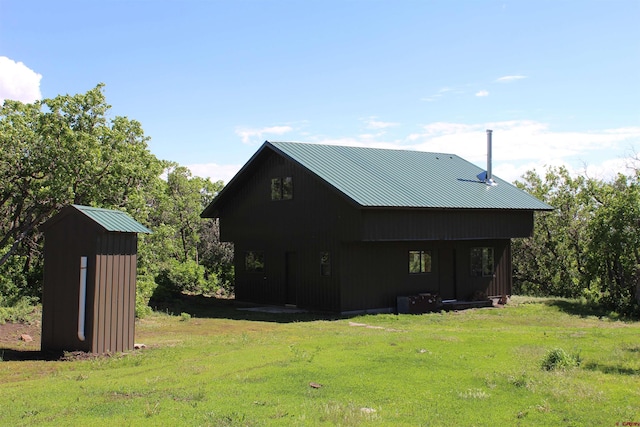 back of property featuring a storage shed and a yard